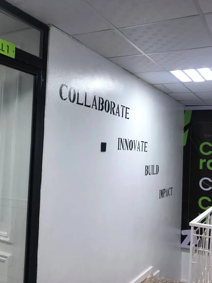 A wall reading Collaborate, Innovate, Build, Impact beside a branded poster